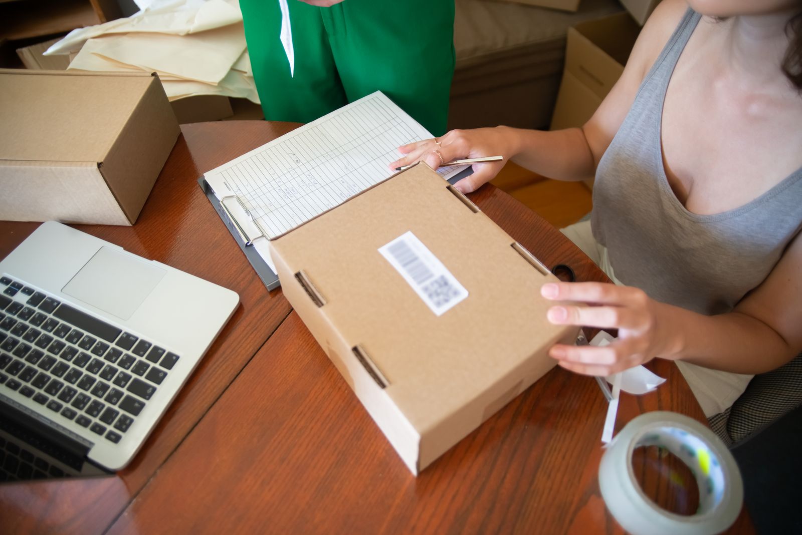 Two independent online sellers packing orders together beside a laptop