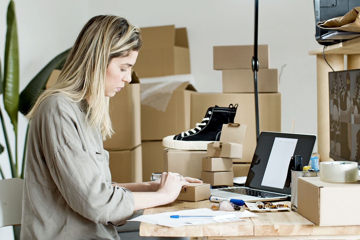 An independent online seller preparing customer orders beside a laptop